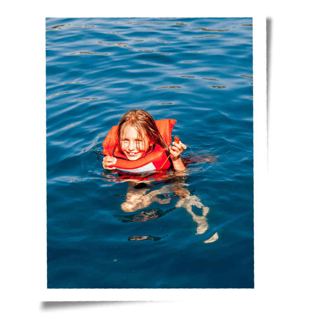 Barnet simmar i vattnet i räddningsväst.