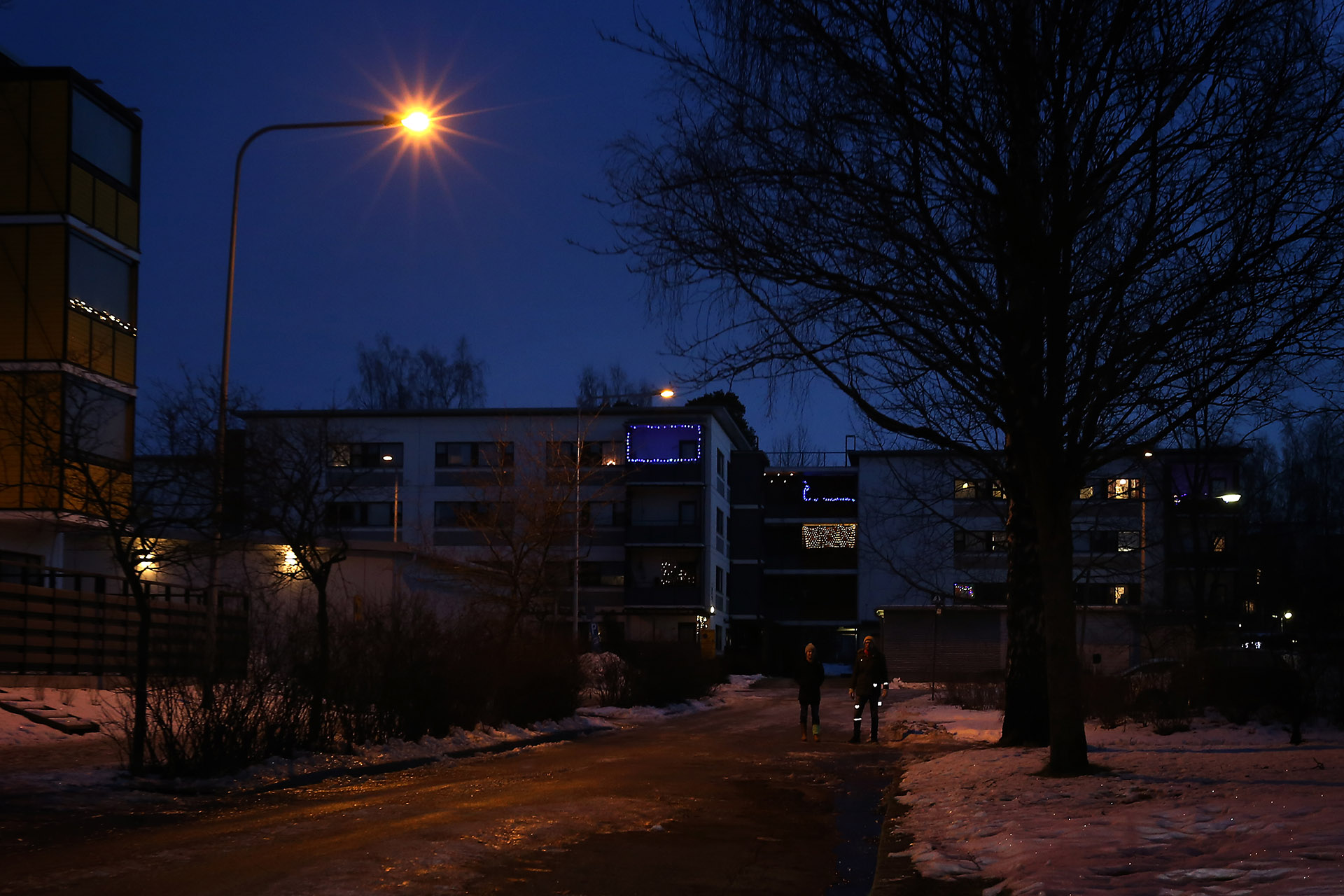 Kaksi henkilöä pimeässä: toinen näkyvissä heijastimien ansiosta ja toinen ei.